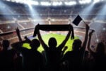 Fans celebrating inside a packed stadium during a large-scale sporting event requiring temporary structure fire code compliance.